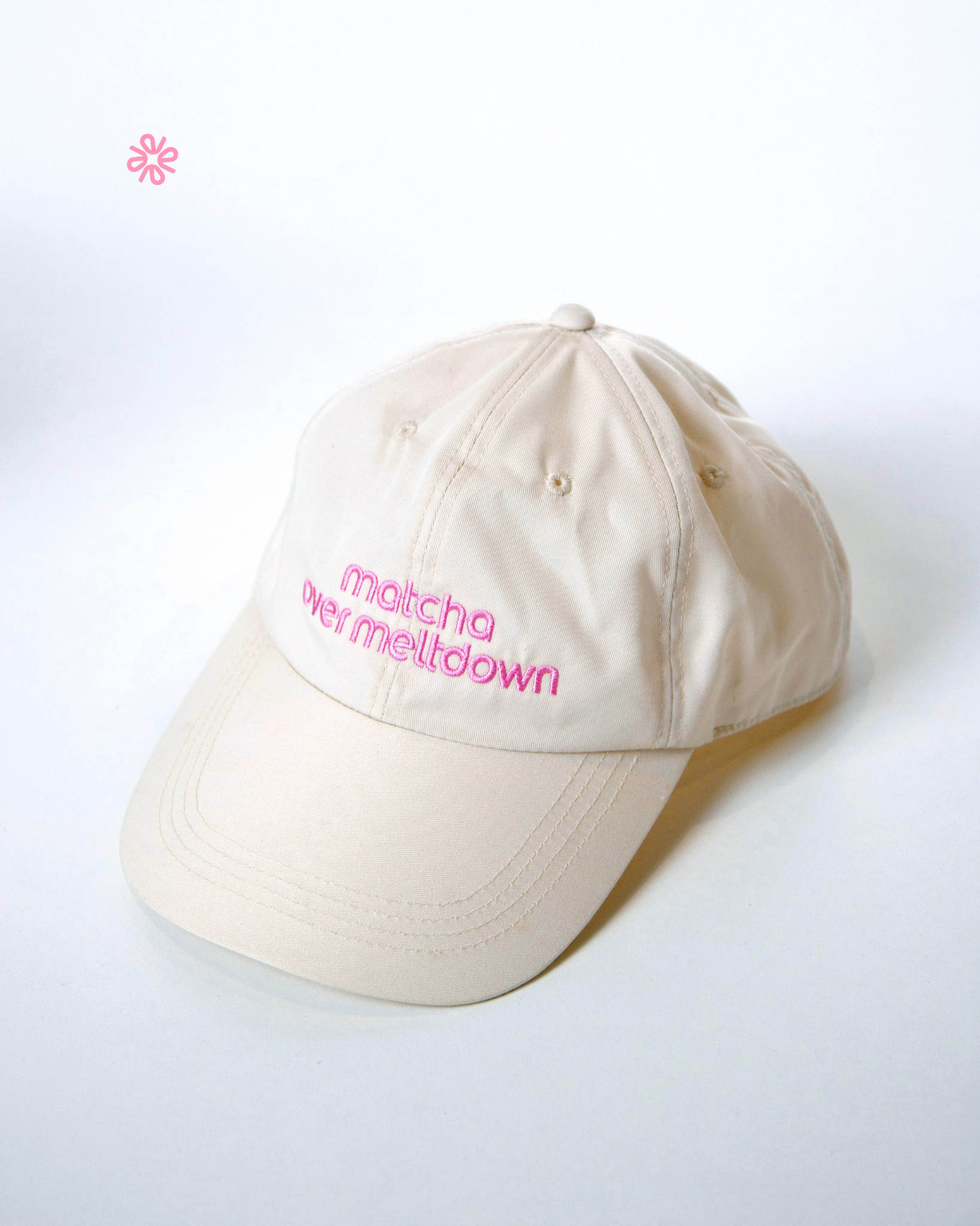 Beige cap with pink text on a white background