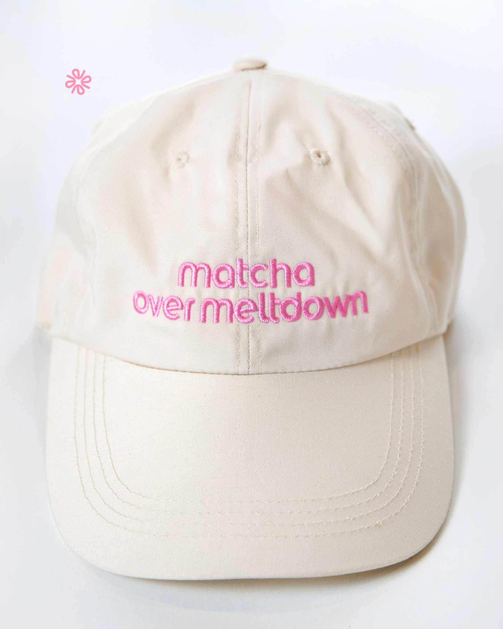Beige cap with pink text 'matcha over meltdown' on a white background